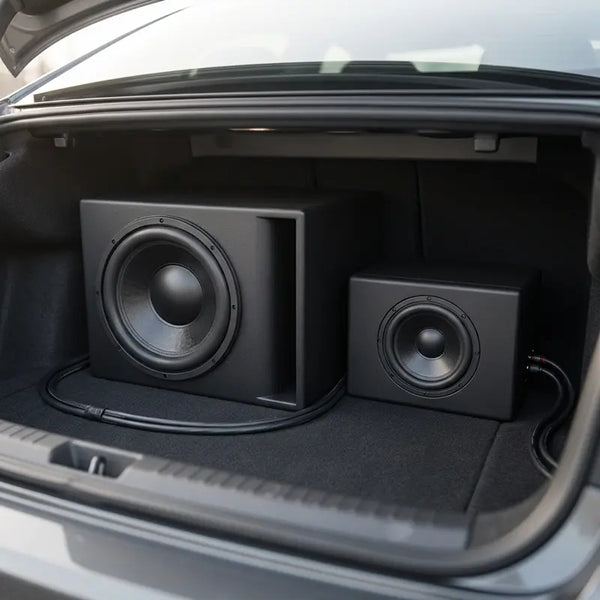 Großer und kompakter Subwoofer im Größenvergleich nebeneinander im Kofferraum